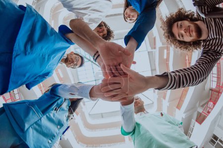 Photo for A group of doctors and a medical nurse join their hands together, showcasing the unwavering teamwork and solidarity that drives their collective efforts in the healthcare field. - Royalty Free Image