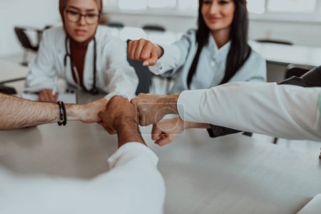 A group of doctors and a medical nurse join their hands together on a table, showcasing the unwavering teamwork and solidarity that drives their collective efforts in the healthcare field.