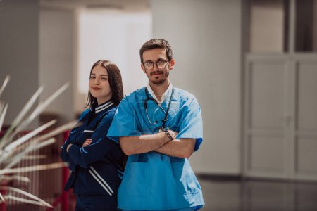 Foto de Un médico y una enfermera están de pie con confianza con los brazos cruzados en el pasillo de un hospital moderno, exudando profesionalidad, trabajo en equipo y dedicación. - Imagen libre de derechos