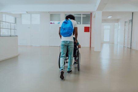 Téléchargez les photos : Étudiant afro-américain poussant ses amis en fauteuil roulant dans une école moderne, démontrant l'inclusion, l'accessibilité et le pouvoir de l'amitié.. - en image libre de droit