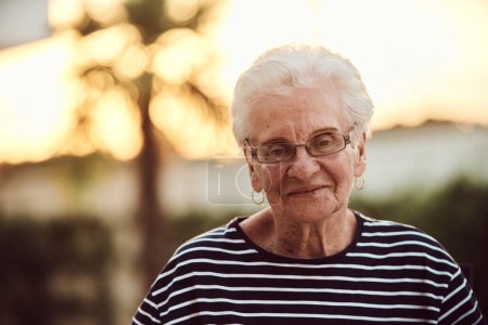Foto de Retrato sin filtro, una verdadera anciana se sienta graciosamente en una silla, mostrando la autenticidad del envejecimiento con arrugas y una cara natural. - Imagen libre de derechos