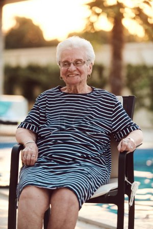 Foto de Retrato sin filtro, una verdadera anciana se sienta graciosamente en una silla, mostrando la autenticidad del envejecimiento con arrugas y una cara natural. - Imagen libre de derechos