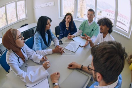 Photo for A dedicated group of doctors and medical nurses attentively listens to their colleagues work plan in a healthcare facility, fostering collaboration and ensuring high-quality patient care. - Royalty Free Image