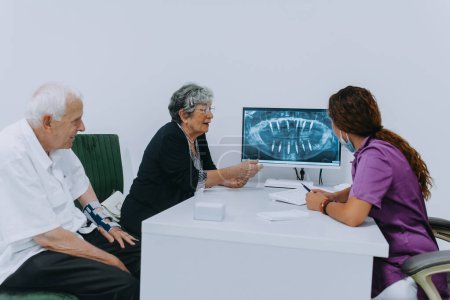 Una pareja de ancianos se involucra en una discusión reflexiva con su dentista sobre las opciones de prótesis dentales modernas en un entorno de consultorio dental contemporáneo.