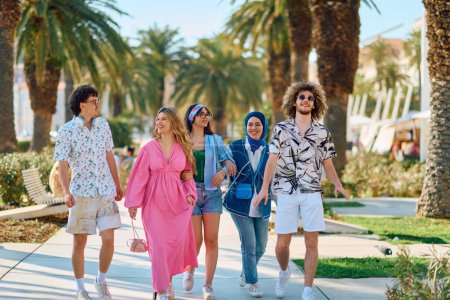Eine bunte Gruppe von Touristen in Sommerkleidung schlendert mit breitem Lächeln durch die Touristenstadt und genießt ihr Sightseeing-Abenteuer. 