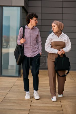 After a day at the office, a business man engages in conversation with his Muslim colleague wearing a hijab. 