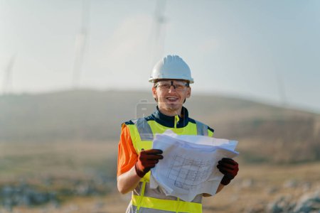 An engineer holding a paper project of a wind turbine for electricity production