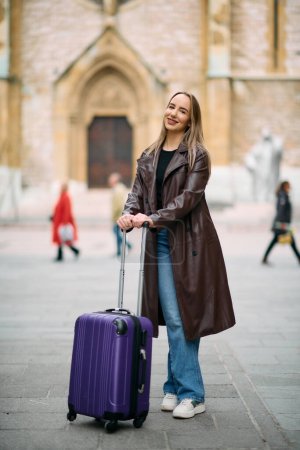 Eine schöne Frau mit einem Koffer geht auf eine touristische Reise in europäische Städte, Konzept des Tourismus, eine sexy Frau geht zu modernen touristischen Orten, eine Frau genießt die Straßen einer modernen europäischen Stadt. 
