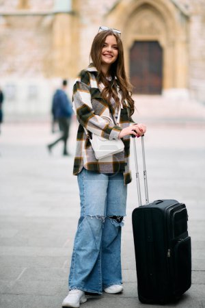 A beautiful woman with a suitcase goes on a tourist trip to European cities, concept of tourism, a sexy woman goes to modern tourist locations, a woman enjoys the streets of a modern European city. 