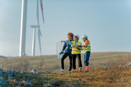 A team of engineers and workers oversees a wind turbine project at a modern wind farm, working together to ensure the efficient generation of renewable energy. 