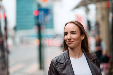 Una mujer con estilo exuda confianza mientras camina por las calles urbanas, vistiendo una chaqueta de cuero de moda.