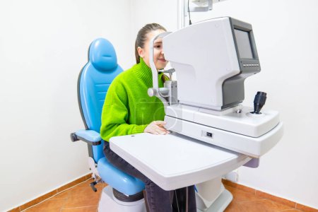 A woman is comfortably seated in a medical chair having her eyes checked by an ophthalmologist using specialized equipment in a hospital setting