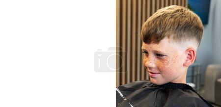 The process of creating mens hairstyles. Hairdressers. Blond boy with freckles on his face and alabaster eyes, the picture taken for the advertisement of a new barbershop. High quality photo