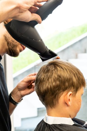 Angenehm erfahrener Friseur mit Haartrockner. Hochwertiges Foto