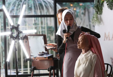 Téléchargez les photos : Belle jeune femme en hijab assis à la table et en utilisant son ordinateur portable - en image libre de droit