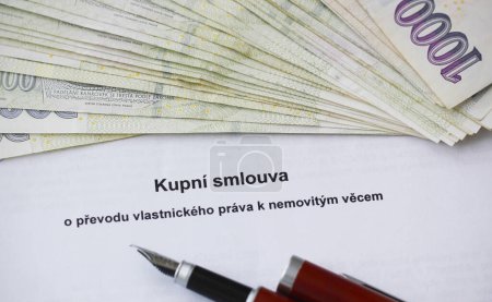 Close-up of a purchase contract on the transfer of ownership rights to real estate written in Czech language and a pack of Czech banknotes. Concept for ownership, legal issues and legal documents.