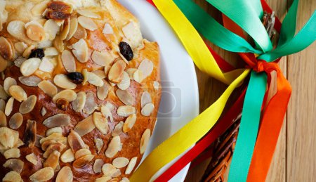 Close-up of a traditional Czech Easter sweet cake called "mazanec" and an Easter handmade whip with colorful ribbons on wooden table. Top view