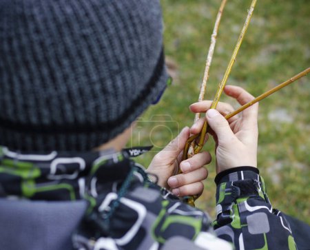 Close-up of boy's hands braiding an Easter whip from fresh willow twigs, a traditional Czech and Slovak symbol of Easter, used by boys to carol on Easter Monday.