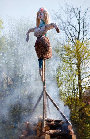 A funny dummy of a witch attached to a wooden cross on a bonfire with smoke rising from it on the day of the burning of witches celebrated in the Czech Republic on the 30th April
