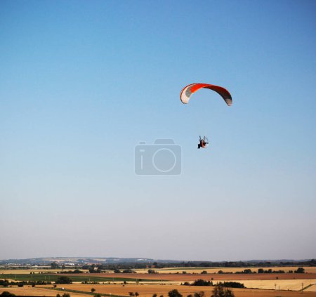 Silhouette d'un homme volant un parapente motorisé dans le ciel bleu au-dessus d'un paysage plat. Activités sportives de plein air extrêmes. Espace négatif, espace de copie.