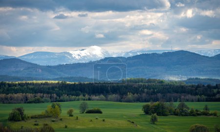Téléchargez les photos : Vue sur le sommet enneigé de la montagne Sniezka avec des champs verts printaniers dans les montagnes Kaczawskie - en image libre de droit