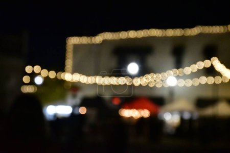 Téléchargez les photos : Un bâtiment flou avec des lumières de Noël et des gens émouvants dans l'obscurité - en image libre de droit