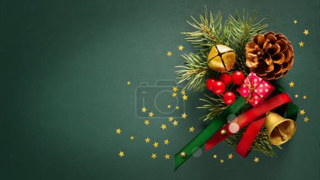 Téléchargez les photos : Composition de carte de Noël en coffret cadeau, branches de sapin, cône, cloches sur un fond vert. Pose plate, vue du dessus, espace de copie - en image libre de droit