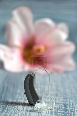 Photo for Close-up auditory rothesis with a flower in the background symbolizing the ear. - Royalty Free Image
