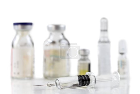 Foto de Jeringa frente a una oleada de vacunas sobre un fondo blanco. - Imagen libre de derechos