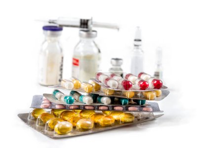 Foto de Surtido de píldoras de medicamentos farmacéuticos, tabletas y cápsulas, vial de vidrio y jeringa con vacuna o antibiótico. Sobre fondo blanco. - Imagen libre de derechos