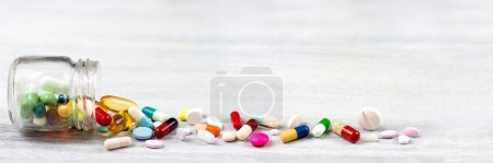 Foto de Primer plano panorámico de los medicamentos y cápsulas vistos saliendo de una botella de vidrio - Imagen libre de derechos