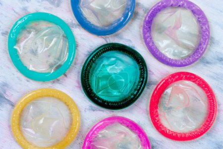 Foto de Preservativos de varios colores apilados en el centro bajo, vistos desde arriba. - Imagen libre de derechos