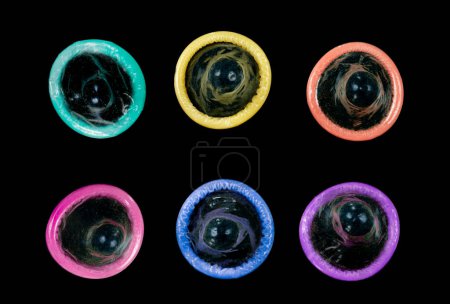 Foto de Preservativos de colores alineados en dos filas sobre un fondo negro. - Imagen libre de derechos
