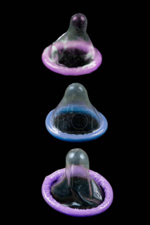 Foto de Preservativos de colores alineados verticalmente sobre fondo negro. - Imagen libre de derechos