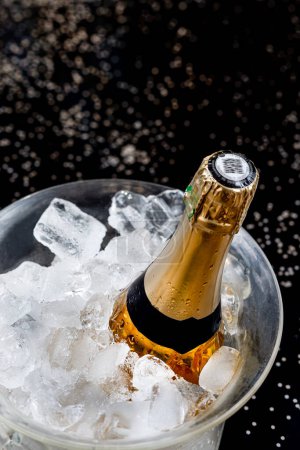 Téléchargez les photos : Bottle of Champagne in an ice bucket on a festive background and straw huts - en image libre de droit