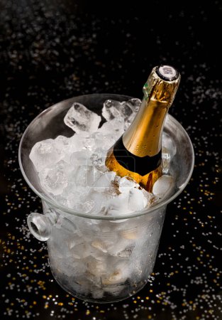 Téléchargez les photos : Bottle of Champagne in an ice bucket on a festive background and straw huts - en image libre de droit