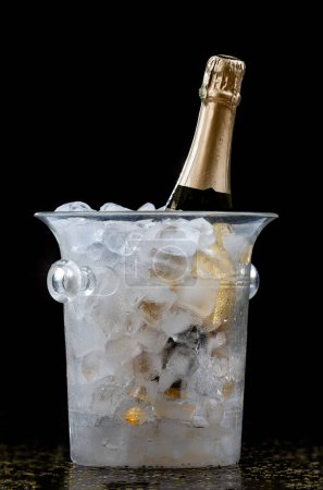 Photo for Bottle of Champagne in an ice bucket on a festive background and straw huts - Royalty Free Image