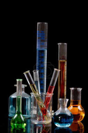 Foto de Laboratory equipment and color chemicals on dark background - Imagen libre de derechos