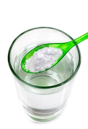 Foto de Cuchara de bicarbonato de sodio sobre un vaso de agua, aislado en blanco - Imagen libre de derechos