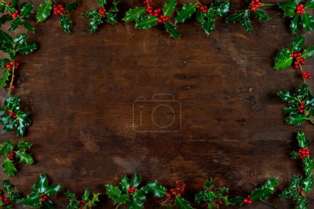 Foto de Verdor de invierno de Navidad y la baya de acebo borde de fondo abstracto en tablero de madera. elemento para tarjeta de felicitación, etiqueta de regalo, etiqueta, menú, invitación. - Imagen libre de derechos