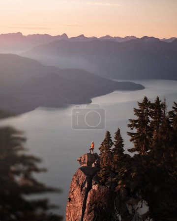 Foto de Girl standing on a mountain peak looking at the scenery - Imagen libre de derechos