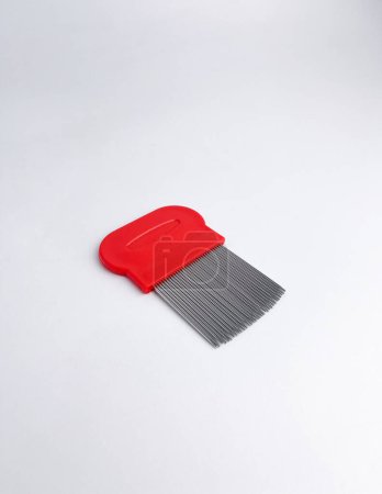 Haarfloh oder Zeckenentfernungskamm mit rotem Griff und Bürstenmaterial aus Edelstahl. Objektfotografie isoliert auf vertikalem weißem Hintergrund.