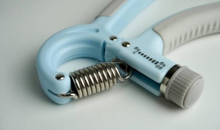 Close up spring spiral part of light blue and gray colored hand grip exercise tool obect photography isolated on ratio plain light gray background.