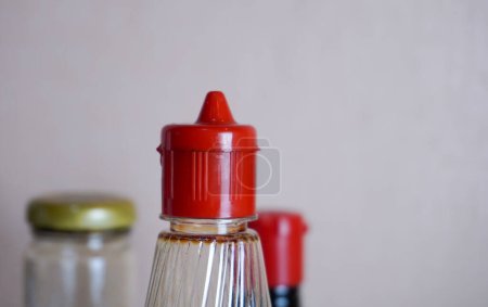 Téléchargez les photos : Fermer condiment de cuisson rouge ingrédient de sauce dans un récipient de bouteille en plastique isolé sur fond horizontal ratio mur. - en image libre de droit