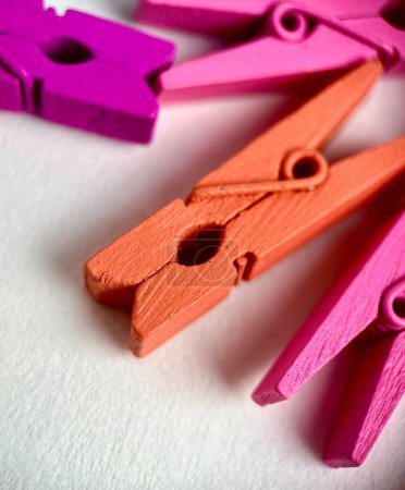 Close up colorful painted wooden pegs clip clothes pin stationary object photography isolated on vertical background.