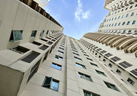 Look up pov sur haut et haut appartement ou immeuble de bureaux façade avec fenêtres et ciel bleu ensoleillé fond horizontal.