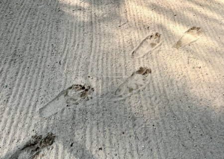Foto de Pie humano impresiones en arena pequeño suelo texturizado con sol cálido sombra sombra piso horizontal fondo. - Imagen libre de derechos