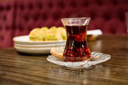 Téléchargez les photos : Savourez l'essence de l'hospitalité turque avec une tasse de thé fumante, parfaitement associée à un biscuit délicieux. En toile de fond, la vue séduisante de nos délices de baklava attend - en image libre de droit