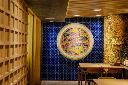 Photo for Immerse yourself in the modern tranquility of a Japanese restaurant featuring a soothing blue wall adorned with a round canvas abstract art painting - Royalty Free Image