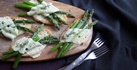 Asparagus and cheese bruschetta on wooden cutting board. Directly above. Healthy food.